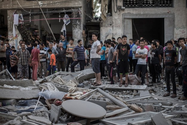 Palestyńczycy w Strefie Gazy na gruzach budynku zniszczonego w izraelskim nalocie /Oliver Weiken /PAP/EPA