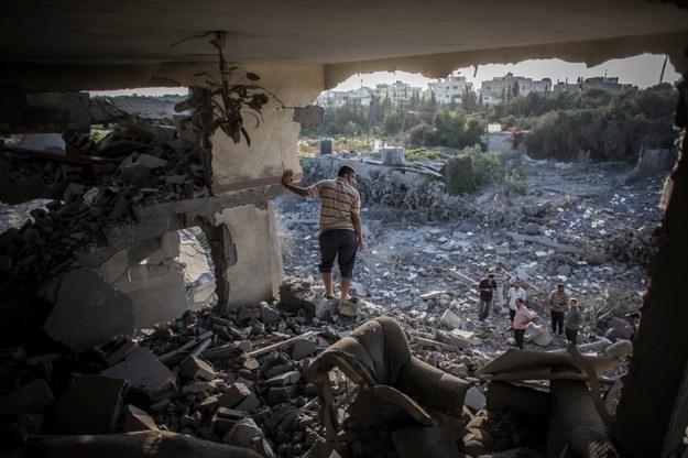 Palestyńczyk na gruzach swojego domu tuż po izraelskim nalocie /Oliver Weiken /PAP/EPA