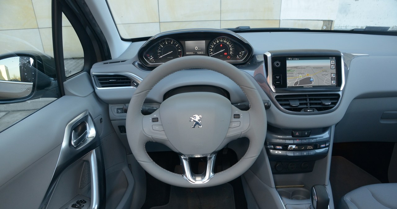 Peugeot 208 1.0 VTi Active: Jasnoszare materiały rozjaśniają wnętrze 208, ale mają dwie wady – łatwo się brudzą (zwłaszcza w dolnej części), a w słoneczny dzień deska rozdzielcza odbija się w szybie. /Motor