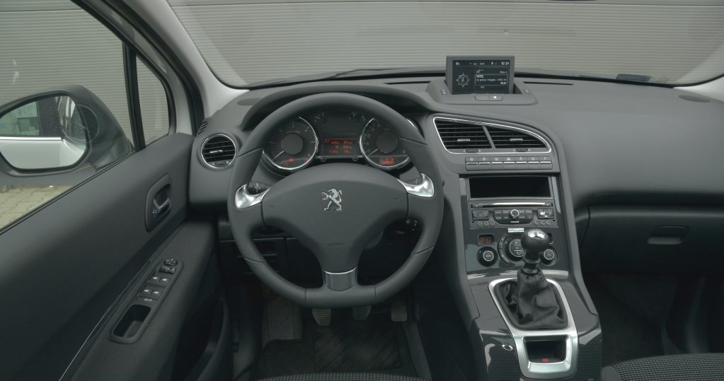 Peugeot 5008 2.0 HDi 150 Allure: na kierownicy nie ma przycisków zestawu audio, ale pod nią jest wygodny joystick. Świetne umiejscowienie przekładni zmiany biegów i tylko jeden uchwyt na kubek. Wysoka jakość górnej części kokpitu. /Motor