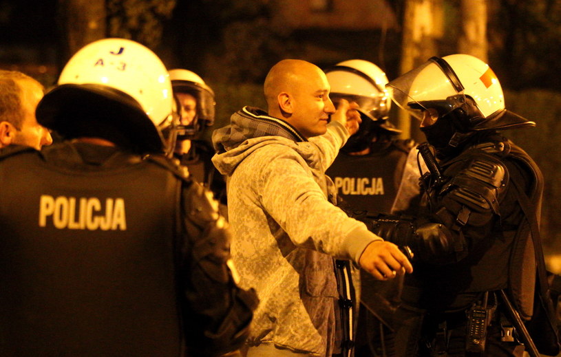 Policjanci przeszukują pseudokibiców, którzy próbowali wzniecić zamieszki przed komisariatem /Andrzej Grygie /PAP