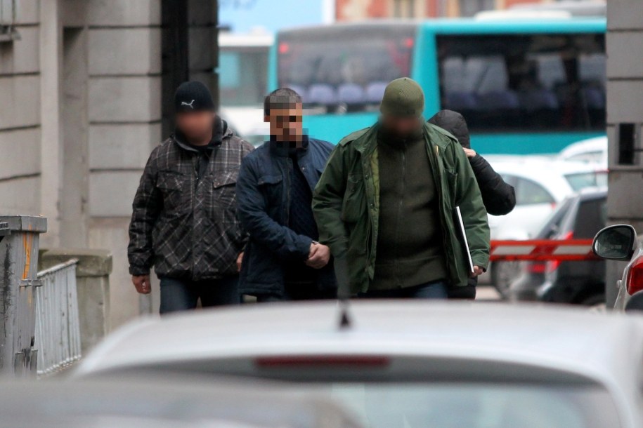 Policjanci wyprowadzają z Prokuratury Okręgowej w Gdańsku jednego z podejrzanych (C) w sprawie parabanków /Piotr Wittman /PAP