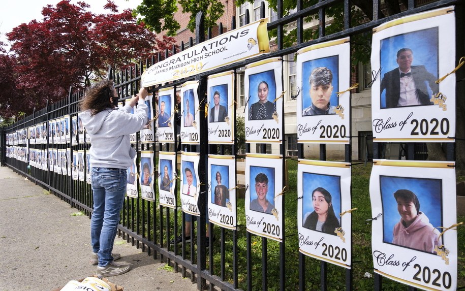 Pracownica jednej z nowojorskich szkół wieszająca na ogrodzeniu placówki zdjęcia uczniów kończących w tym roku edukację /JUSTIN LANE /PAP/EPA