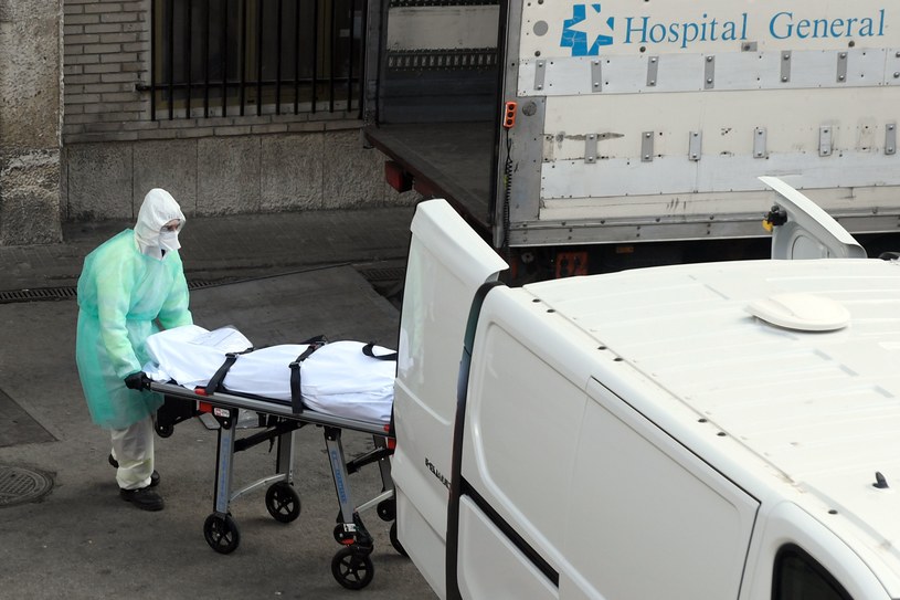 Pracownik włoskiej służby zdrowia ładuje ciało do samochodu /OSCAR DEL POZO /AFP