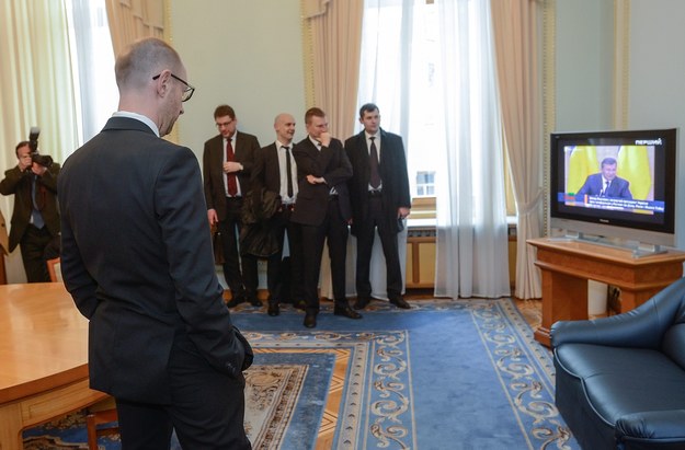 Premier Ukrainy Arsenij Jaceniuk (po lewej) i jego współpracownicy oglądają w telewizji konferencję prasową Wiktora Janukowycza /Andrew Kravchenko /PAP/EPA