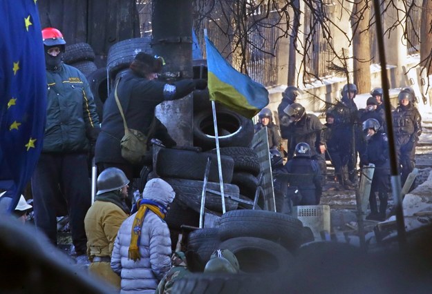 Protestujący na barykadzie, w tle funkcjonariusze milicji /MAXIM SHIPENKOV    /PAP/EPA