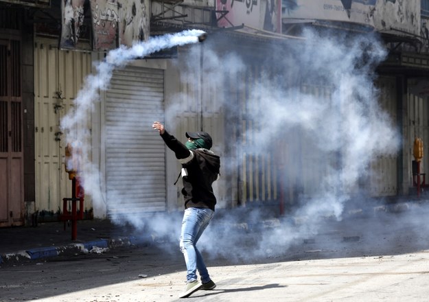 Protesty, demonstrujące solidarność ze Strefą Gazy, objęły całe terytorium Autonomii Palestyńskiej. Na zdjęciu: Palestyńczyk odrzuca granat z gazem łzawiącym rzucony przez wojska izraelskie w czasie starć w mieście Hebron /ABED AL HASHLAMOUN    /PAP/EPA