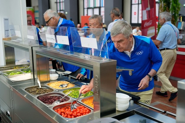 Przewodniczący MKOl Thomas Bach (z przodu) próbuje potraw z baru sałatkowego podczas zwiedzania wioski olimpijskiej przed Igrzyskami Olimpijskimi Paryż 2024. /Xinhua/ABACA /PAP