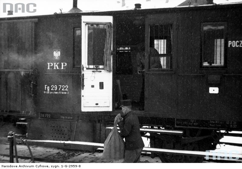 Przewóz poczty. Mężczyzna z workiem pocztowym stoi przed wagonem pocztowym na peronie, 1931 /Z archiwum Narodowego Archiwum Cyfrowego
