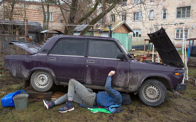 Rosjanin naprawiający swoją Ładę pod blokiem /Getty Images