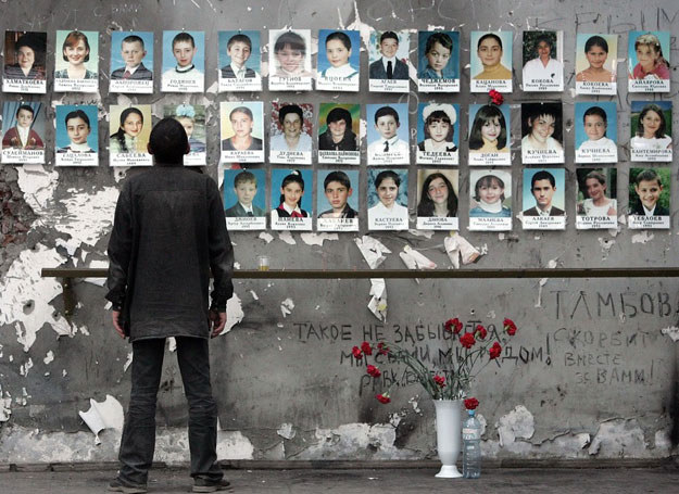 Ruiny szkoły w Biesłanie. Mężczyzna ogląda zdjęcia ofiar /YURI KADOBNOV/ AFP /East News