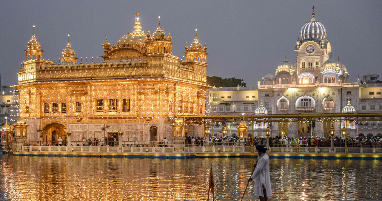 Sewadar (wolontariusz) wiosłuje łodzią w świętym basenie na tle oświetlonej Złotej Świątyni w rocznicę urodzin Guru Angad Dev Ji, drugiego guru Sikhów,  Amritsar 1 maja 2022 roku. (Foto: NARINDER NANU / AFP) /East News