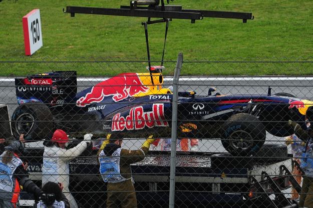 Służby porządkowe usuwają z toru rozbity bolid Sebastiana Vettela /AFP