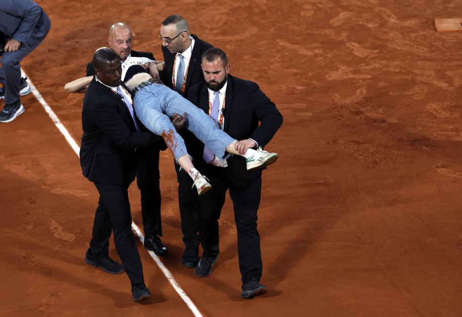 Służby porządkowe wynoszą kobietę z kortu /YOAN VALAT  /PAP/EPA