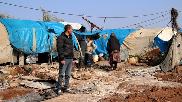 Syryjscy uchodźcy przed namiotem zniszczonym przez pocisk moździerzowy wystrzelony przez Ludowe Jednostki Samoobrony. /AREF WATAD /PAP/EPA