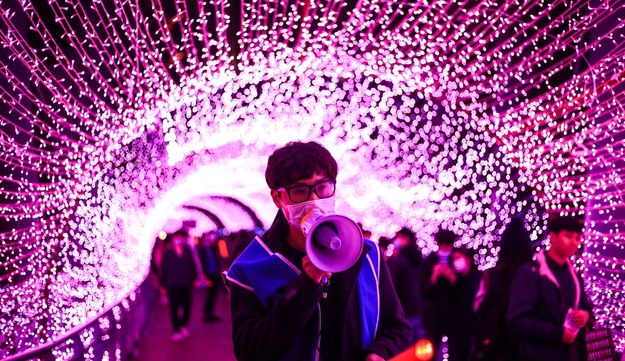 Tajwański wolontariusz przez megafon przypomina ludziom o noszeniu maseczek podczas spaceru pod świątecznymi dekoracjami /RITCHIE B. TONGO /PAP/EPA