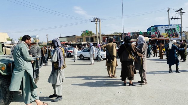 Talibowie stojący na straży, podczas gdy Afgańczycy zbierają się przed lotniskiem w Kabulu, aby uciec z kraju. /PAP/EPA