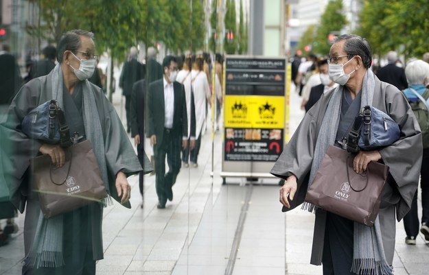 Tokio - przechodzień w maseczce i jego odbicie w szybie /FRANCK ROBICHON /PAP/EPA