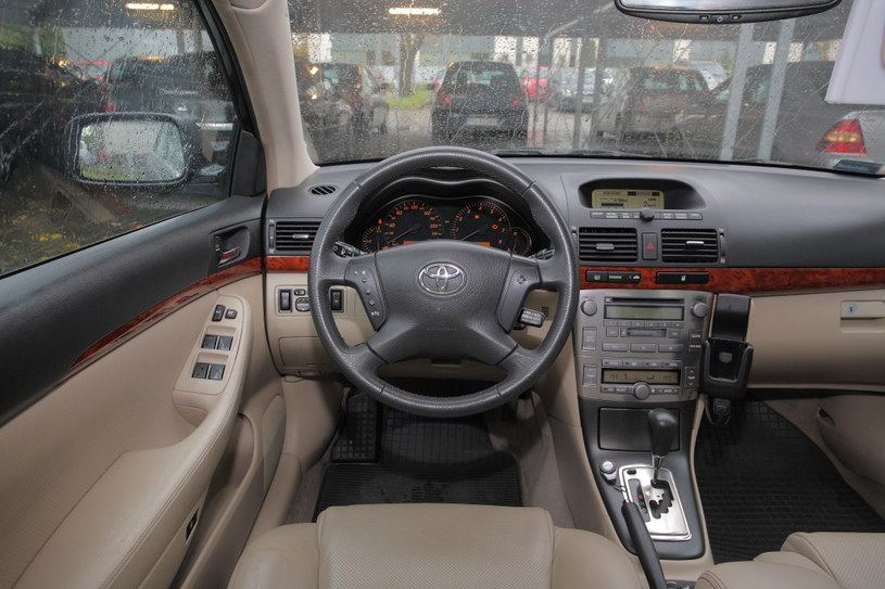 Toyota Avensis II: tak wygląda tablica przyrządów w bogatej odmianie – ze srebrno-drewnianymi wykończeniami i automatyczną klimatyzacją. Większość aut ma ekran komputera nad konsolą. /Motor
