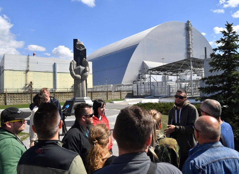 Turyści przed reaktorem czwartym elektrowni czarnobylskiej, zabezpieczonym "sarkofagiem" /SERGEI SUPINSKY /AFP