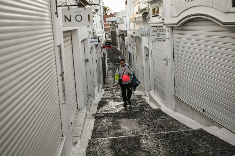 Turysta spaceruje pustą ulicą z zamkniętymi sklepami w mieście Fira na greckiej wyspie Santorini. 04.02.2025 r. /ARIS MESSINIS / AFP /East News