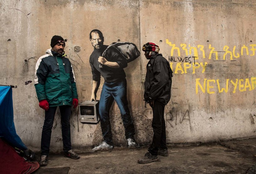Uchodźcy pozujący przy muralu Banksy'ego w Calais. /AFP