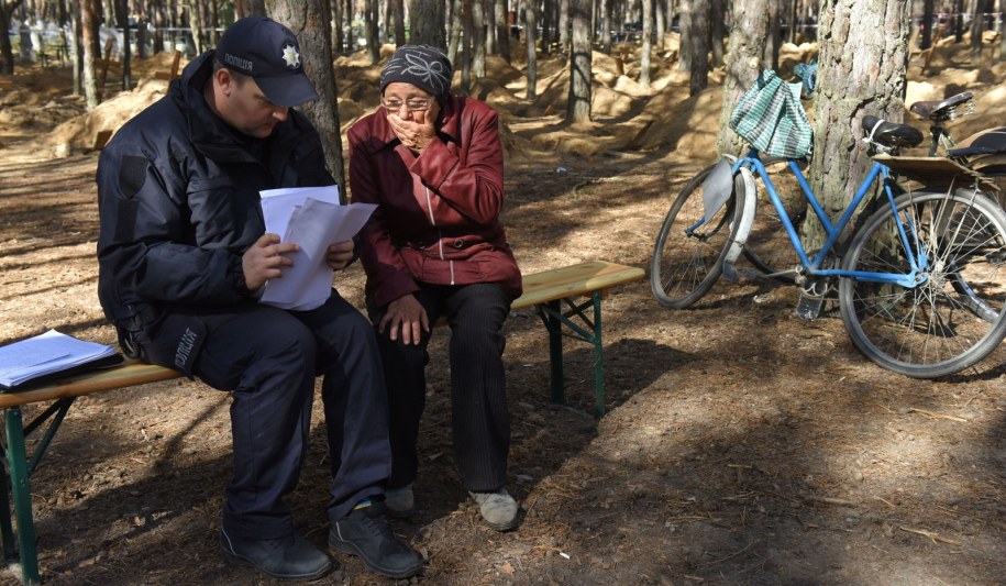 Ukrainka rozmawiająca z policjantem na cmentarzu w Iziumie /OLEG PETRASYUK /PAP/EPA