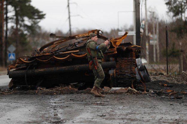 Ukraiński żołnierz robiący zdjęcie obok spalonego rosyjskiego czołgu /ATEF SAFADI  /PAP/EPA