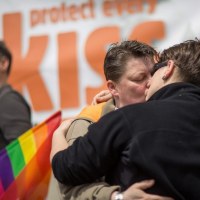 Para całująca się pod plakatem "chroń każdy pocałunek".