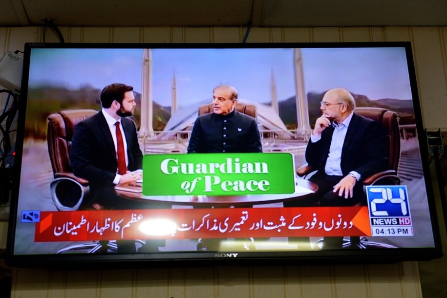 Wiceprezydent USA J.D. Vance (po lewej) z premierem Pakistanu Shehbazem Sharifem (w środku) i przewodniczącym parlamentu Iranu Mohammadem Bagherem Ghalibafem (po prawej) na ekranie telewizora podczas rozmów USA-Iran w Peszawarze w Pakistanie, 11 kwietnia 2026 r.