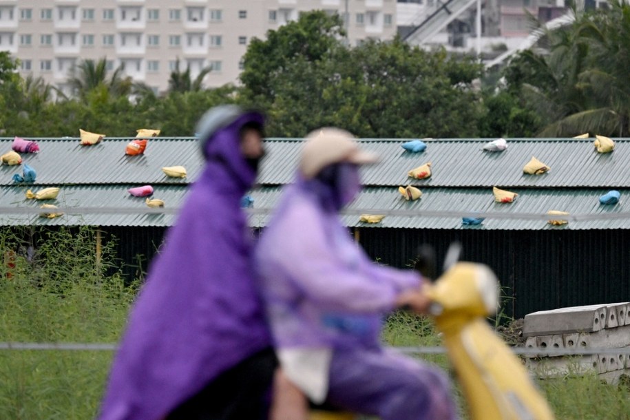 Wietnamczycy mijający dom w prowincji Quang Ninh, na którego dachu umieszczono worki z piaskiem, aby zabezpieczyć go przed zniszczeniem /Nhac NGUYEN / AFP /East News