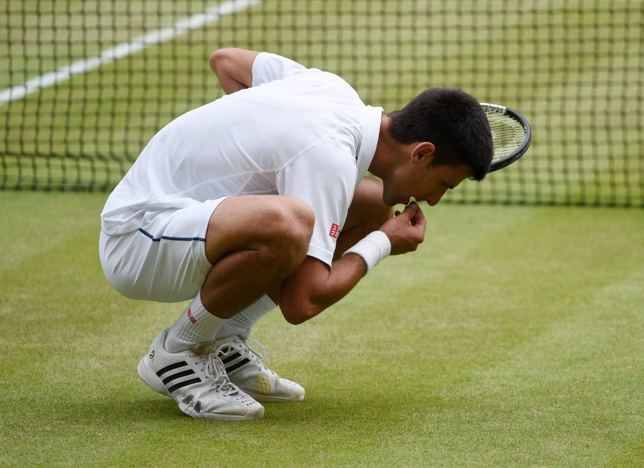 Wimbledon 2015: Novak Djoković je źdźbło trawy po zwycięstwie /FACUNDO ARRIZABALAGA /PAP/EPA
