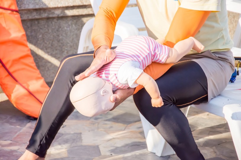 Właściwe ułożenie niemowlęcia podczas próby usunięcia ciała obcego z dróg oddechowych /123RF/PICSEL