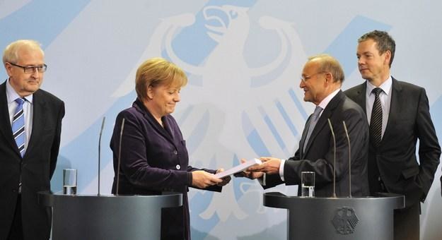 Wolfgang Franz, prezes Rady Ekspertów Gospodarczych przekazuje dokumenty kanclerz Angeli Merkel /AFP