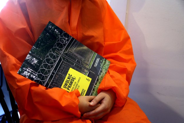 Wolontariusz Amnesty International w przebraniu więźnia czyta raport podczas konferencji prasowej Amnesty International /Tomasz Gzell /PAP