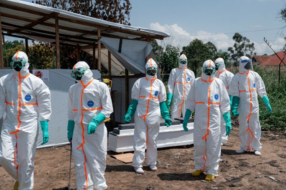 Wolontariusze Czerwonego Krzyża, ubrani w środki ochrony osobistej, gromadzą się wokół trumny z ciałem ofiary wirusa Ebola; zdjęcie z 8 czerwca 2026 r. /JOSPIN MWISHA/AFP /East News