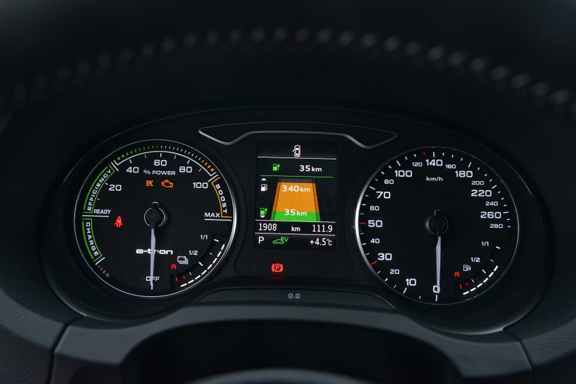 Zamiast obrotomierza – wskaźnik wykorzystania mocy. Grafika pośrodku pokazuje zasięg auta – osobno „na prądzie” (zielona część) i na benzynie (żółta część). /Motor
