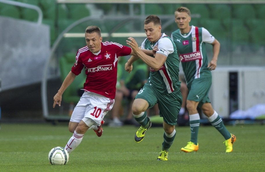 Zawodnik Wisły Kraków Łukasz Garguła (L) walczy o piłkę z Tomaszem Hołotą (C) ze Śląska Wrocław podczas meczu polskiej Ekstraklasy, 4 bm. Z tyłu biegnie Sylwester Patejuk (P) /Aleksander Koźmiński /PAP