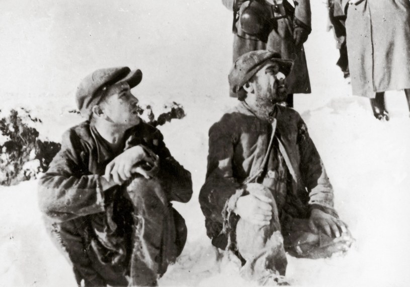 Zdjęcie opisane jako: Polscy Żydzi siedzący w śniegu, w tle niemieccy żołnierze, Bełżec 1942 r. (uwagę zwraca, że mężczyźni nie mają opasek z gwiazdą Dawida) /Imagno /Agencja FORUM