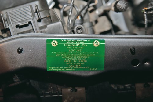 Zielona tabliczka pod maską informuje o rodzaju użytego czynnika (np. R134a) oraz o masie, jaką należy wtłoczyć do układu. Zdjęcie pochodzi z samochodu BMW serii 3. /Motor