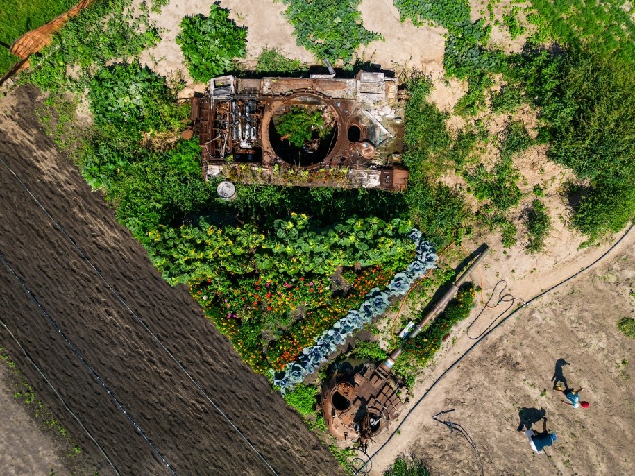 Zniszczony czołg i pracujący w polu ludzie /Vladyslav Musiienko /PAP