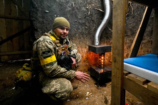 Żołnierz Sił Zbrojnych Ukrainy ogrzewa się w kwaterze mieszkalnej na froncie /Dmytro Smolienko /PAP