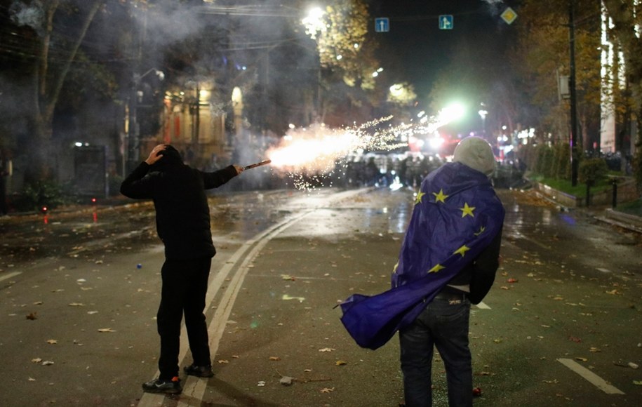 Zwolennik gruzińskiej opozycji rzuca fajerwerki w stronę policji podczas protestu przed budynkiem parlamentu w Tbilisi, Gruzja, 29 listopada 2024 /David Mdzinarishvili  /PAP